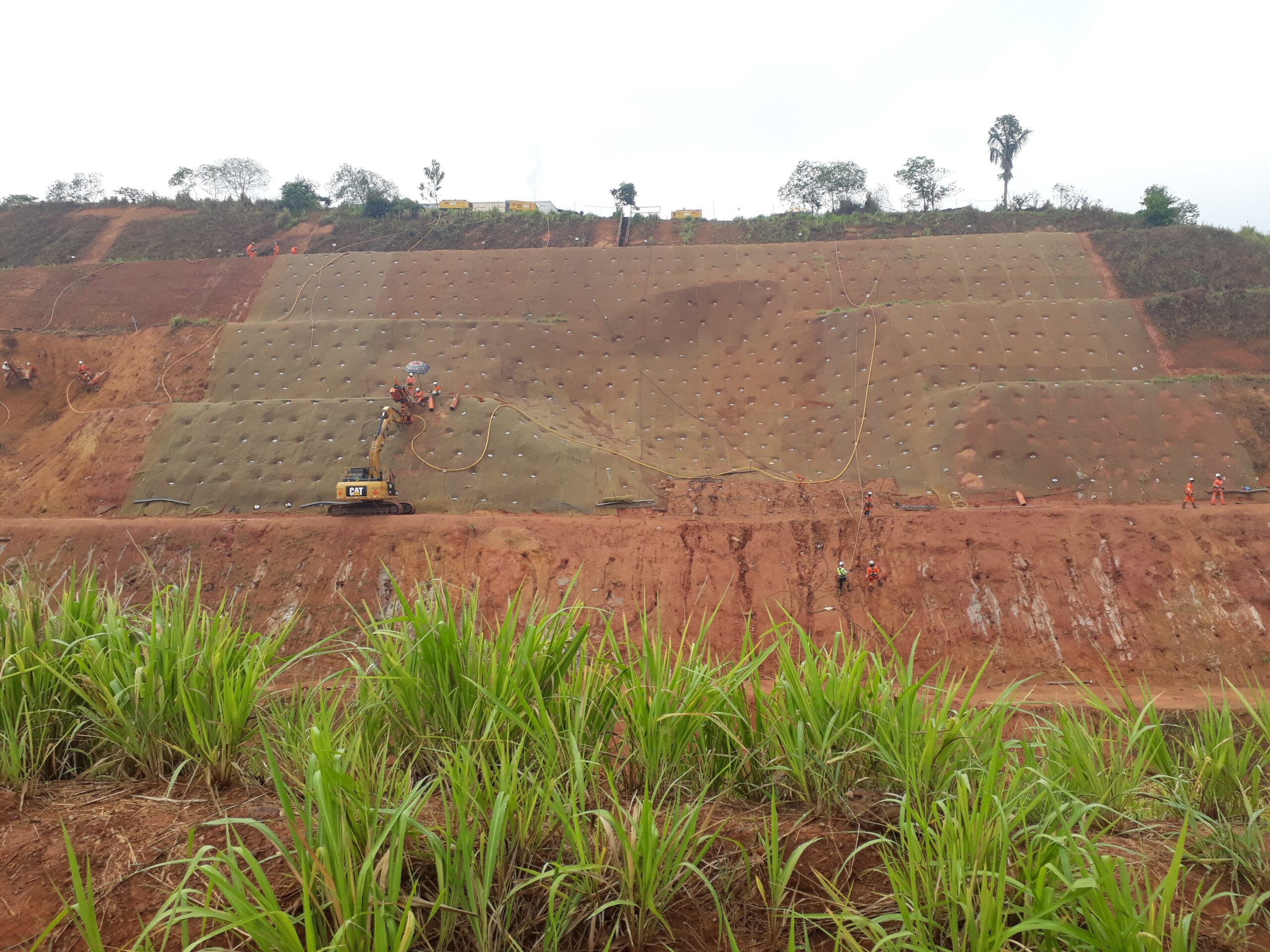 Talude em obra de infraestrutura com equipamento e equipe em campo
